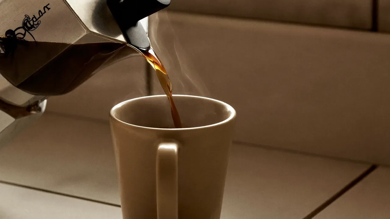コーヒーメーカーから湯気の立つコーヒーがマグカップに注がれている様子